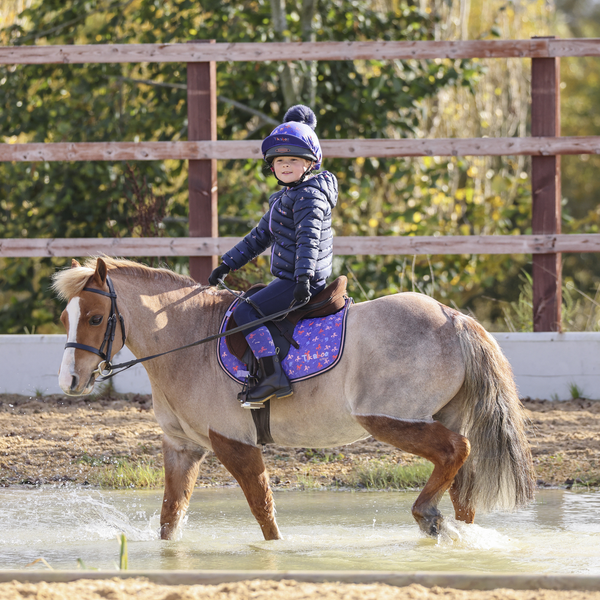 Child riding wearing Tikaboo Padded Coat in Unicorn