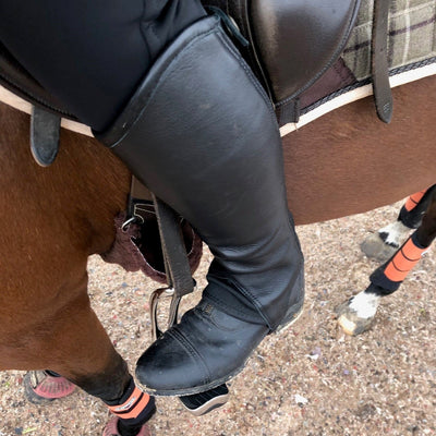 Photo of person wearing black leather jodhpur boots and chaps whilst riding